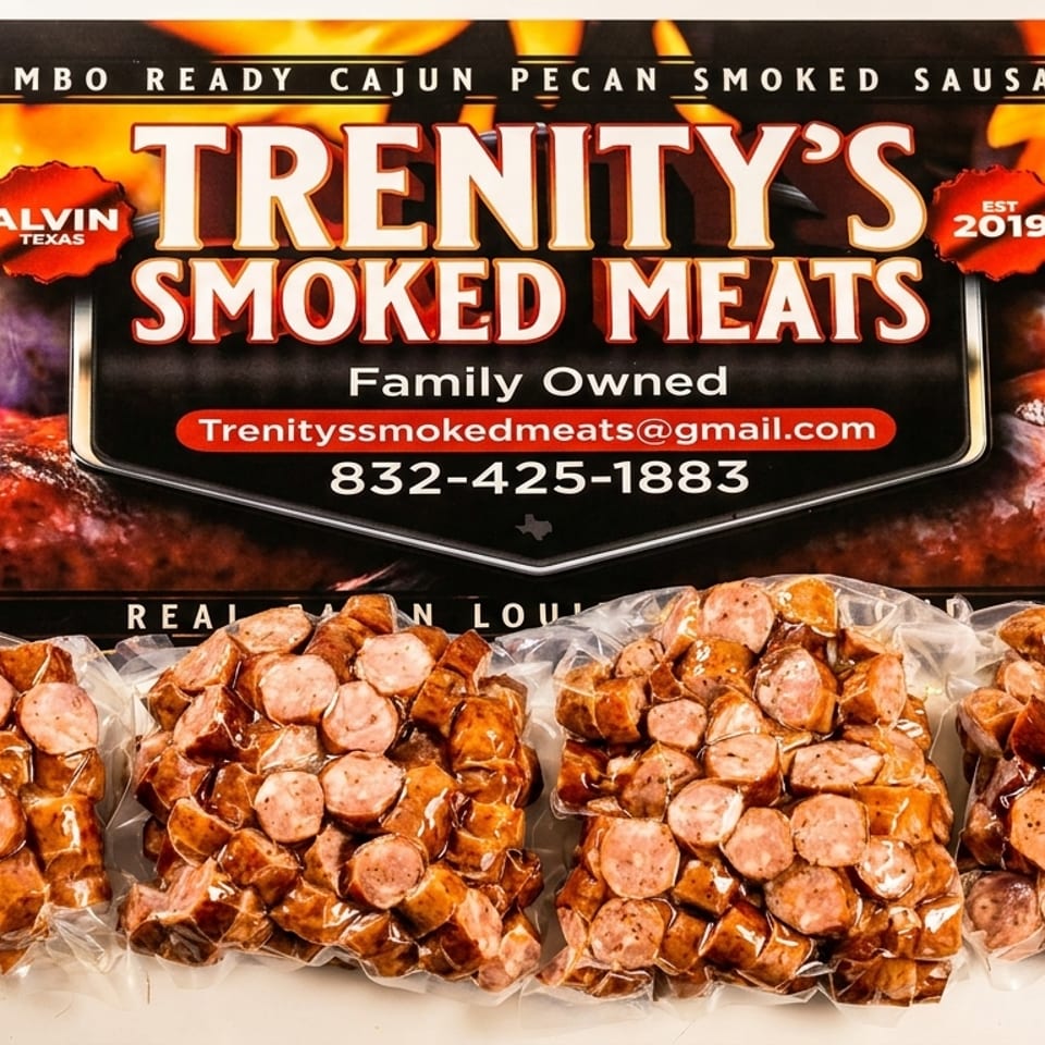 Four vacuum-sealed packages of sliced Trenity's Smoked Meats sausage in front of a brand sign.